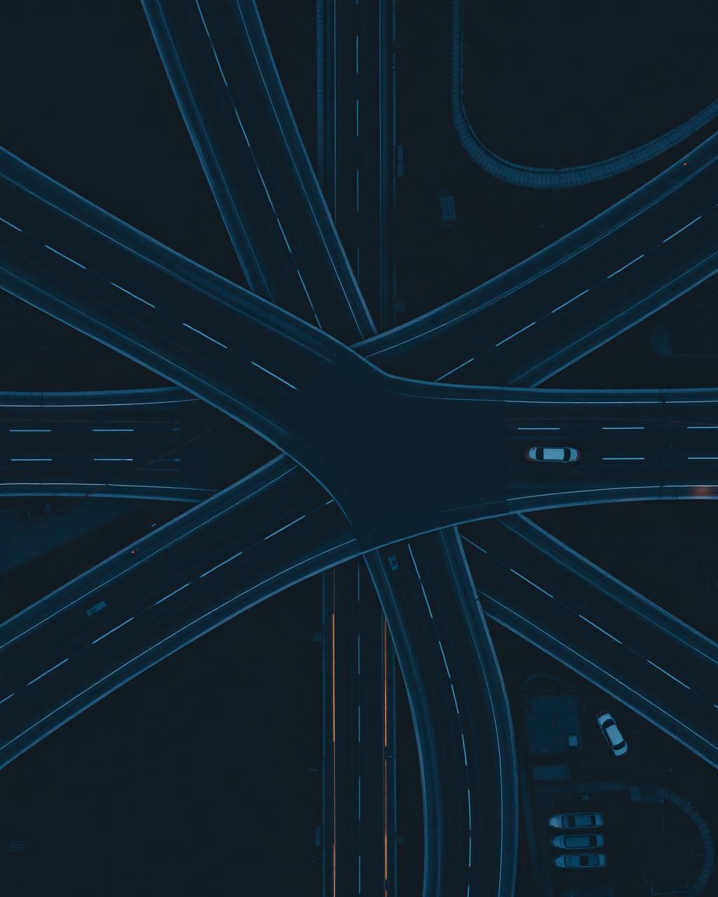 Top-down aerial of a multi-lane highway interchange at dusk